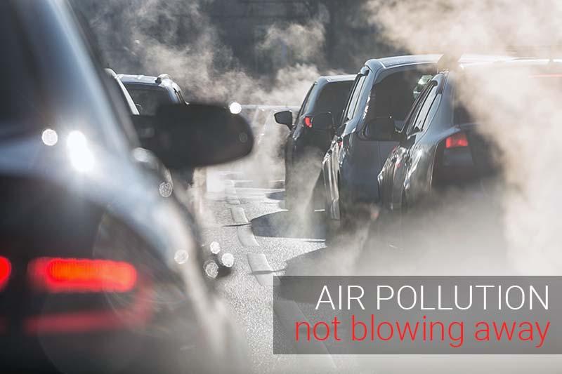 Air pollution news - cars in road with back lit exhaust fumes