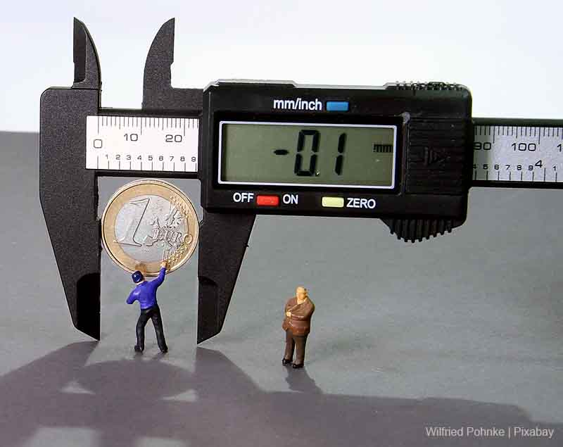 Inflation pressures 2023 - Image of digital caliper measuring a 1 euro coin - display reads 0.1 - indicating shrinkage. Watched by micro workman and supervisor figures.